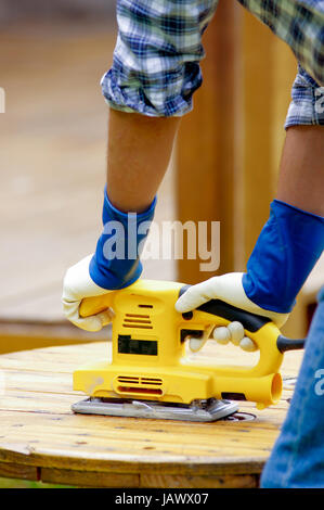 Close up di un uomo utilizzando una smerigliatrice elettrica sul pavimento di pino o tabella Superficie di levigatura Foto Stock