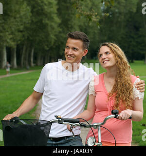 Eine junge Frau und ein junger Mann mit Fahrrädern haben ein Ziel vor Augen Foto Stock