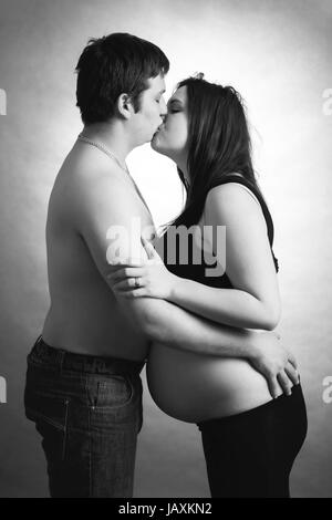 Amorevole coppia felice, donna incinta con il marito e il marito baciare donna, in bianco e nero Foto Stock