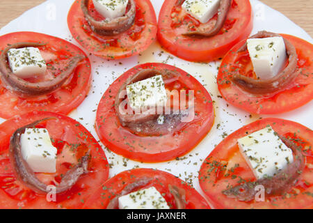 Gustose fette di pomodoro con formaggio e acciughe Foto Stock