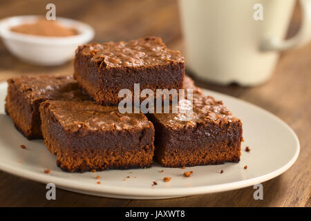 Pane appena sfornato brownie pezzi su una piastra con la coppa in retro (messa a fuoco selettiva, messa a fuoco sulla parte anteriore sinistra della tomaia brownie) Foto Stock