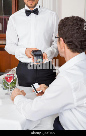Bargeldlose zahlung im restaurant mit kreditkarte abendessen paar geld Foto Stock