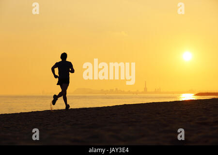 Silhouette pareggiatore correre sulla spiaggia al tramonto con l'orizzonte in background Foto Stock