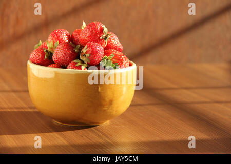 Ciotola riempita con fragole fresche in presenza di luce solare Foto Stock