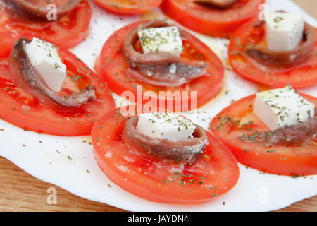 Gustose fette di pomodoro con formaggio e acciughe Foto Stock