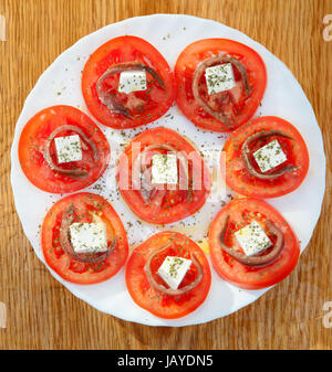 Gustose fette di pomodoro con formaggio e acciughe Foto Stock