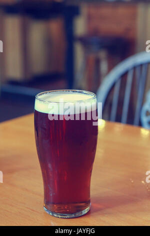 Bicchiere grande di ale scure su un tavolo in un pub Foto Stock