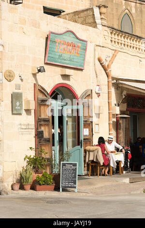 Un uomo e una donna seduta al di fuori del ristorante Terrone di Marsaxlokk Malta nella luce del sole di mangiare al fresco Foto Stock