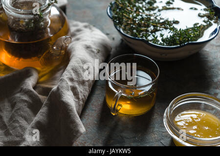 Bollitore con tè verde, il timo e il miele sul tavolo orizzontale Foto Stock