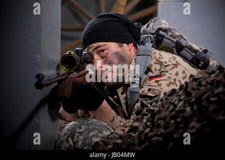 Uomo armato in passamontagna nascosto dietro un muro Foto stock