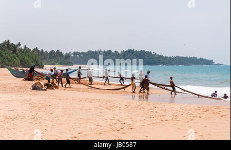 KOSGODA, SRI LANKA - 23 febbraio: i pescatori locali tirare una rete da pesca da Oceano Indiano il 23 febbraio 2013 in Kosgoda, Sri Lanka. La pesca in Sri Lanka è il loro modo di guadagnarsi da vivere. Foto Stock