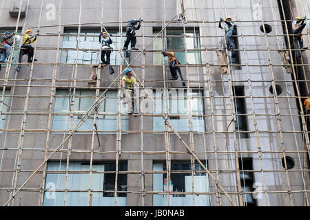 Lavoratori costruire impalcature di bambù al di fuori di un edificio. . Foto Stock