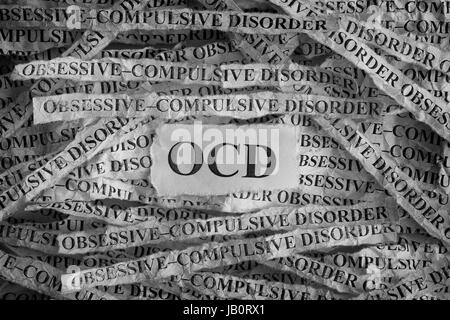 Disturbo ossessivo compulsivo (OCD). Pezzi di carta strappati con le parole del disturbo ossessivo-compulsivo. Concetto di immagine. In bianco e nero. Primo piano. Foto Stock