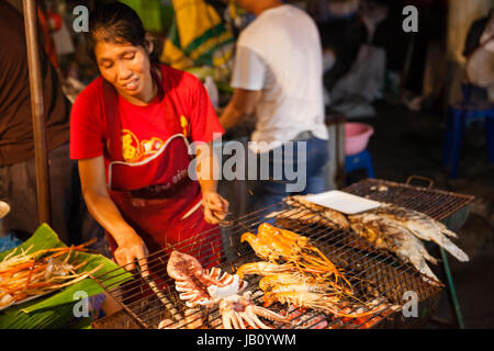 CHIANG MAI, Thailandia - 27 agosto: Donna cuochi di scampi e calamari alla griglia al mercato di domenica (walking street) il 27 agosto 2016 a Chiang Mai, T Foto Stock