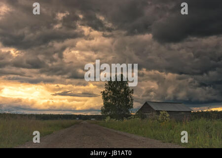 La calda giornata estiva si sta trasformando in un temporale nelle aree rurali della Finlandia. Nuvole pesanti si raccolgono oltre i campi. Foto Stock