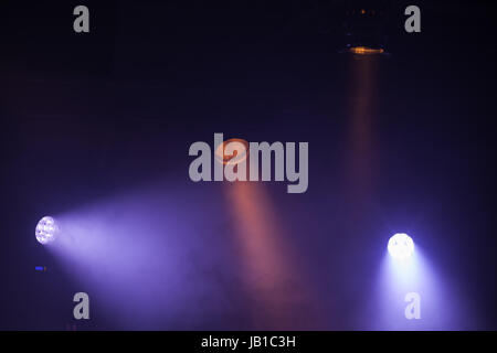 Scenic colorate luci spot con forti travi in dark nebbia, stadio sullo sfondo di illuminazione Foto Stock