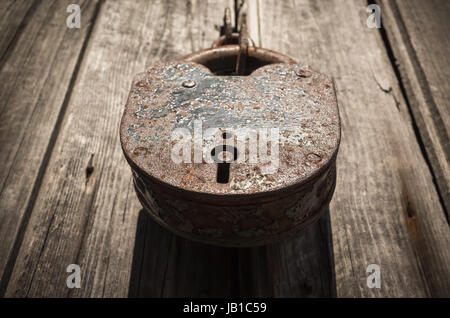 Antico e grande lucchetto arrugginito appeso sulla porta di legno Foto Stock