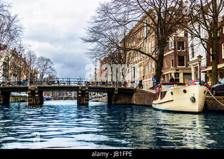 Le biciclette parcheggiate su un ponte su un canale con un cabinato ormeggiate vicino al ponte, Amsterdam, Paesi Bassi Foto Stock