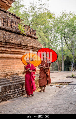 Pochi monaci con ombrello in Myanmar in un antico tempio sotto il sole Foto Stock