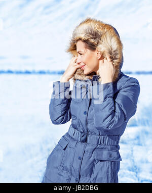 Ritratto di ragazza carina all'aperto in inverno, guardando dal lato, felice e uno stile di vita attivo, abiti alla moda per la stagione invernale Foto Stock