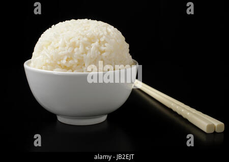 Bianco di riso cotto a vapore nel recipiente di ceramica e bastoncini Foto Stock