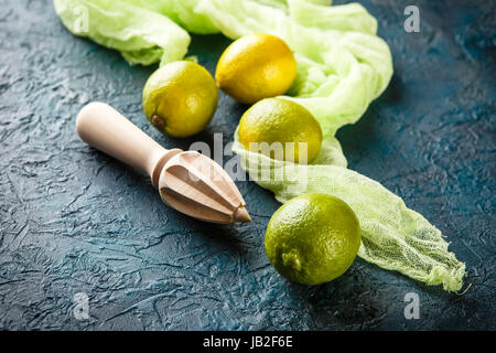 Succosa limes e limone e centrifuga in legno scuro su sfondo turchese Foto Stock