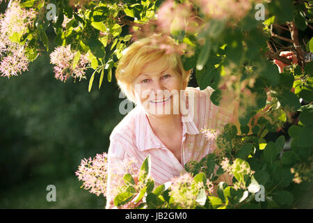 Vivace allegro ottimista Senior donna tra i fiori Foto Stock