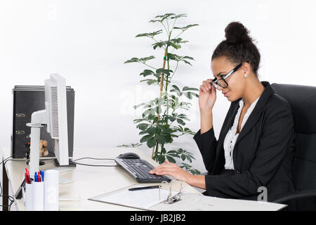 Junge hübsche, Büroangestellte sitzt am Schreibtisch im Büro und schaut konzentriert auf den Monitor Foto Stock