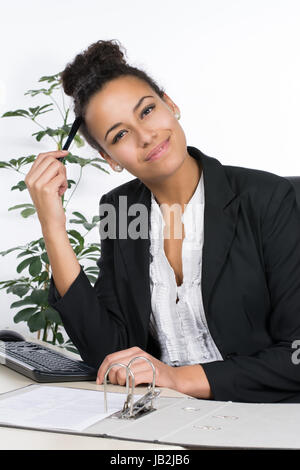 Junge hübsche, Büroangestellte lächelnd sitzt am Schreibtisch im Büro Foto Stock