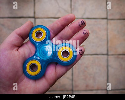 Un immobile agitano: spinner in una mano con volti sorridenti sugli ultimi tre dita Foto Stock