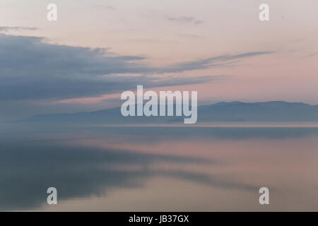 Perfettamente simmetrica nuvole riflessioni su un lago al tramonto Foto Stock