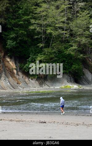 Giovane donna di camminare sulla spiaggia nella baia di tramonto del parco statale, Oregon Foto Stock