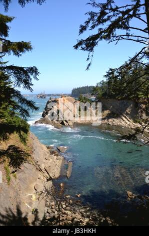 Caletta rocciosa sulla costa dell'Oregon con Cape Arago faro Foto Stock