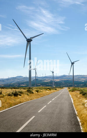 Strada asfaltata attraverso un turbine di vento campo di montagna. Foto Stock