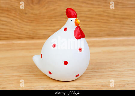 Divertenti in ceramica di gallina bianca e rossa su uno sfondo di legno Foto Stock