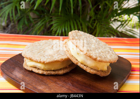 Due noci di cocco mango ice cream sandwich all'esterno da un albero di palma Foto Stock