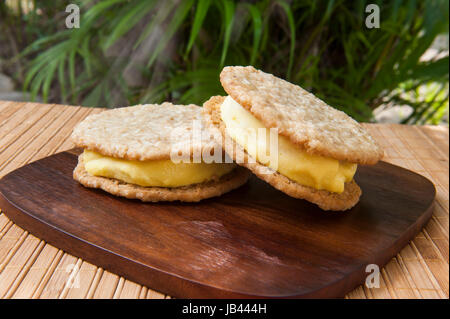 Vegano mango di noce di cocco e farina di avena cookie ice cream sandwich all'aperto ai tropici Foto Stock