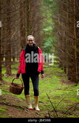 Junge frau mit roter jacke im herbst sammelt pilze im Wald natur entspannung lebensmittel Foto Stock