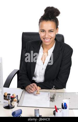 Junge hübsche, Büroangestellte sitzt am Schreibtisch im Büro und stempelt in einen Aktenordner Foto Stock