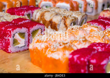 Assortimento di sushi e rotola sul pannello di legno in luce oscura Foto Stock