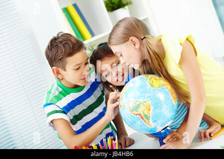 Ritratto di felice i compagni di scuola al lavoro studiando globe in aula Foto Stock