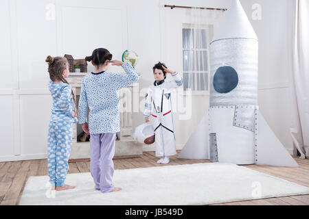 Le ragazze che plaude al ragazzo in costume da astronauta a casa Foto Stock