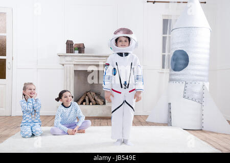 Le ragazze alla ricerca sul ragazzo in costume da astronauta a casa Foto Stock