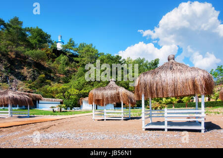 Estate mandrini sulla spiaggia. Vista mozzafiato sul mar Mediterraneo. Legno bianco summerhouses sulla giornata di sole. Cielo blu e nuvole soffici Foto Stock