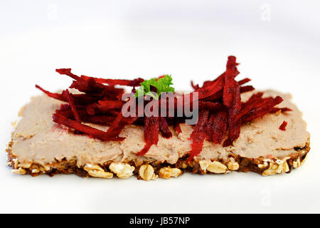 Pezzo di pane scuro con live pate e julienne di barbabietole sulla parte superiore. Foto Stock