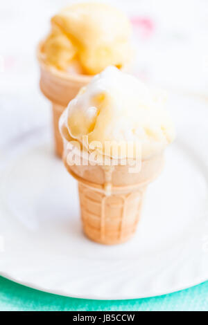 Primo piano dei due coni di gelato al mango sulla piastra bianca Foto Stock