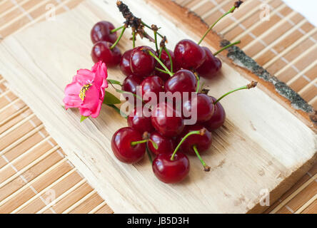 Close up fresco e appetitoso ciliegie su un pezzo di legno isolato su sfondo beige Foto Stock