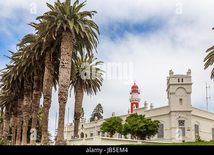 Faro rosso, bianco fort tedesco e la fila di palme, di città coloniale di Swakopmund, Namibia Foto Stock