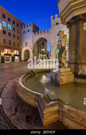 Brunnenbuberl Fontana e Karlstor cancello in serata, Monaco di Baviera, Germania Foto Stock