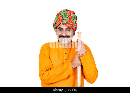 Sorridente 1 rurale indiano abitante Gujrati uomo tenendo un bastone su sfondo bianco Foto Stock